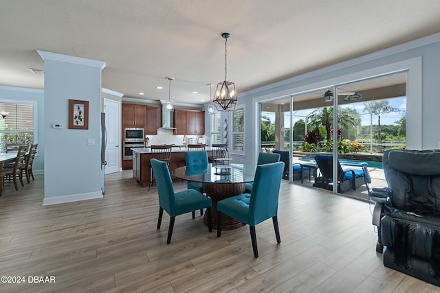 dining area featuring a notable chandelier, ornamental molding, and light hardwood / wood-style flooring