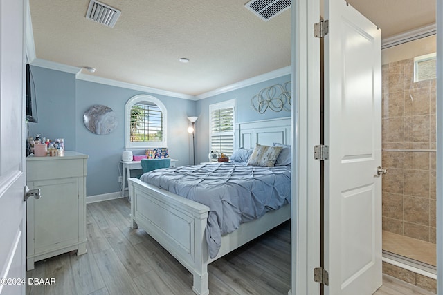 bedroom with light hardwood / wood-style floors, a textured ceiling, and crown molding