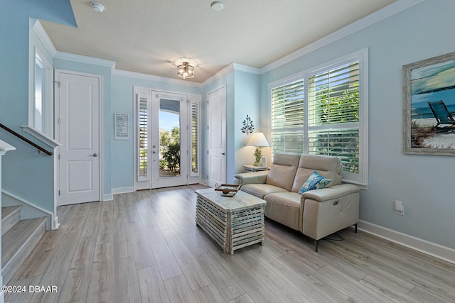 living room with light wood-type flooring, a textured ceiling, a healthy amount of sunlight, and crown molding