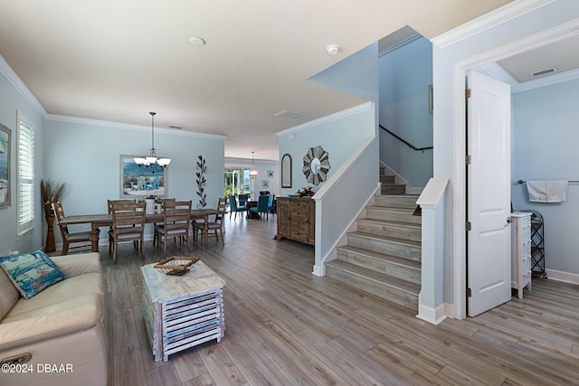 living room featuring wood-type flooring, crown molding, and a notable chandelier