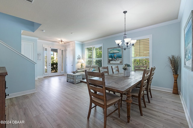 dining space featuring ornamental molding, a chandelier, a textured ceiling, and light hardwood / wood-style floors