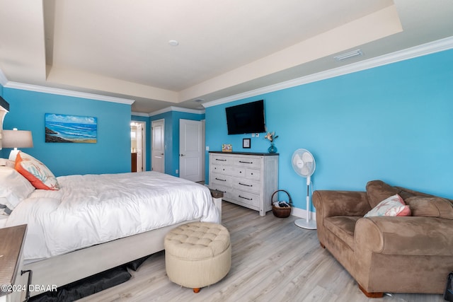 bedroom with a tray ceiling, light hardwood / wood-style floors, and crown molding