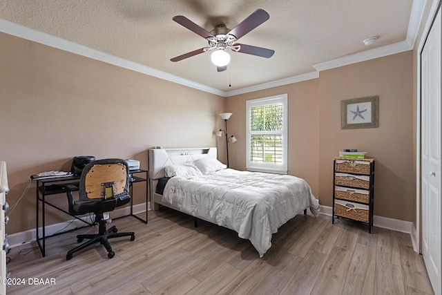 bedroom featuring ceiling fan, a textured ceiling, light hardwood / wood-style flooring, crown molding, and a closet