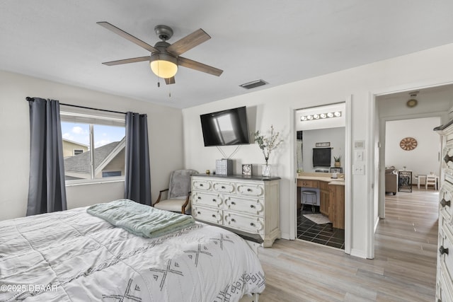 bedroom with ensuite bath, ceiling fan, and light hardwood / wood-style floors