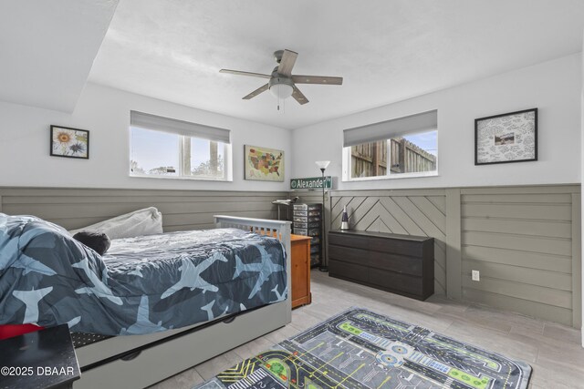 bedroom with ceiling fan and wooden walls