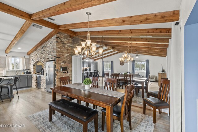 dining room featuring light wood-type flooring, vaulted ceiling with beams, and ceiling fan with notable chandelier