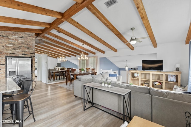 living room with ceiling fan with notable chandelier, light hardwood / wood-style floors, and vaulted ceiling with beams