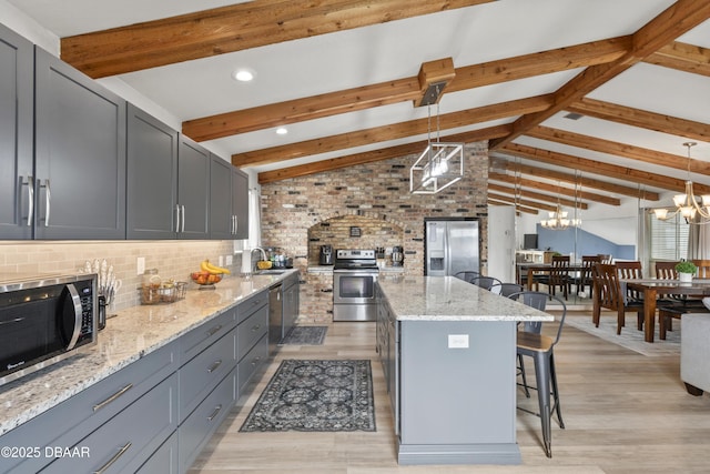 kitchen with stainless steel appliances, lofted ceiling with beams, hanging light fixtures, and a center island