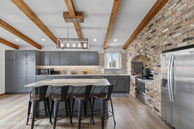 kitchen with stainless steel appliances, light stone countertops, decorative backsplash, a kitchen island, and decorative light fixtures