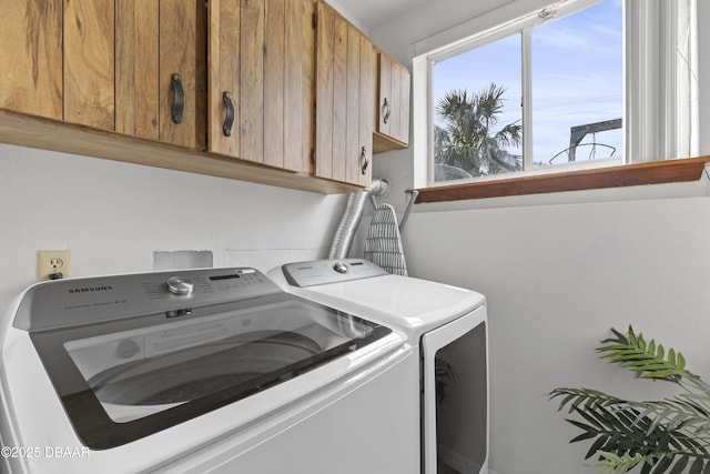 clothes washing area featuring cabinets and washing machine and clothes dryer