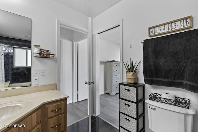 bathroom with toilet, hardwood / wood-style flooring, a textured ceiling, and vanity