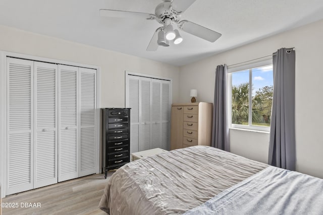 bedroom with multiple closets, ceiling fan, and light hardwood / wood-style floors