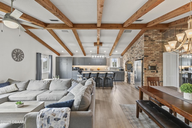 living room with ceiling fan with notable chandelier, wood-type flooring, and vaulted ceiling with beams