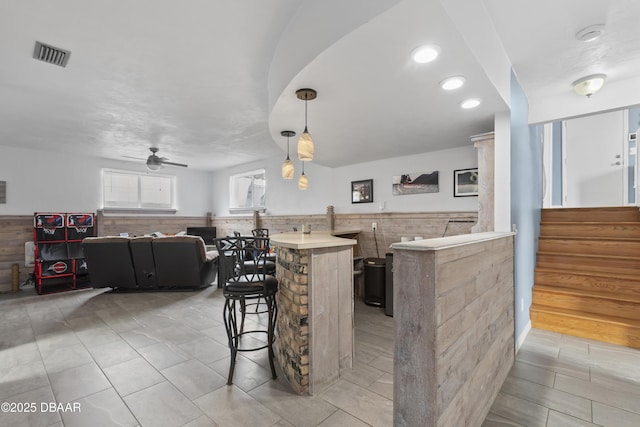 kitchen featuring ceiling fan, light tile patterned floors, kitchen peninsula, a breakfast bar area, and hanging light fixtures