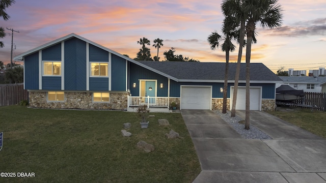 split level home with a lawn, covered porch, and a garage