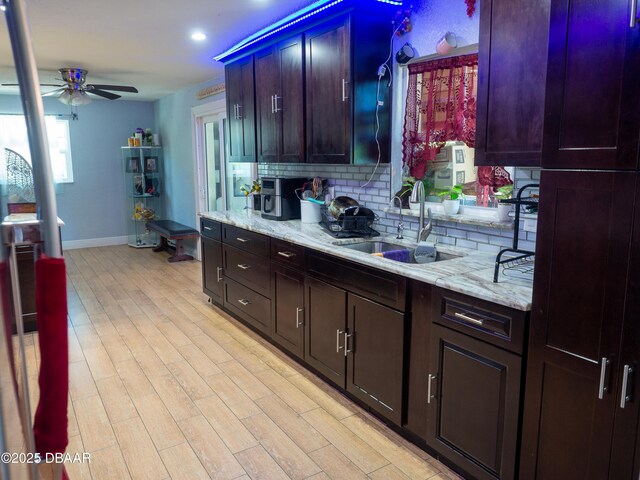1325 Laurel Dr, Daytona Beach, FL 32117 - kitchen featuring a sink, baseboards, a ceiling fan, tasteful backsplash, and light stone counters