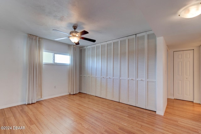 unfurnished bedroom featuring light wood-type flooring, two closets, and ceiling fan