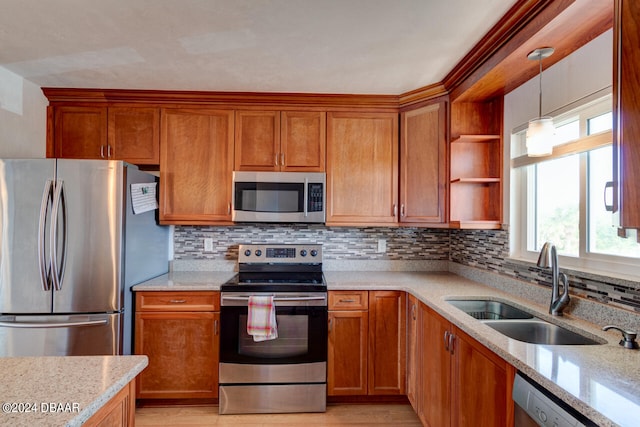 kitchen with stainless steel appliances, light hardwood / wood-style floors, light stone counters, decorative backsplash, and sink