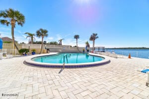 view of swimming pool featuring a water view and a patio area