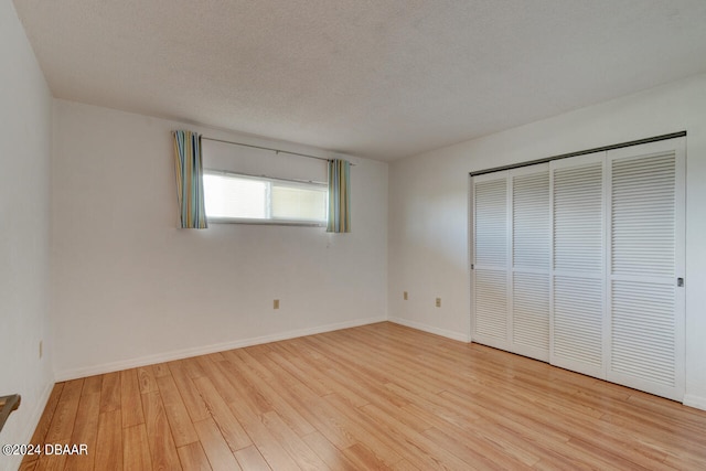 unfurnished bedroom with a closet, a textured ceiling, and light hardwood / wood-style floors