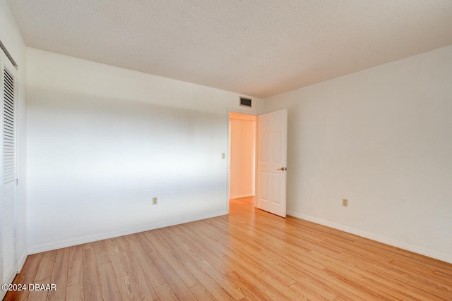 unfurnished room featuring light hardwood / wood-style floors and a textured ceiling