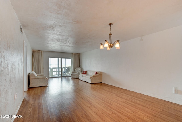 unfurnished living room with a notable chandelier and light hardwood / wood-style flooring