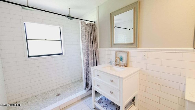 full bath with a wainscoted wall, a shower stall, tile walls, and vanity