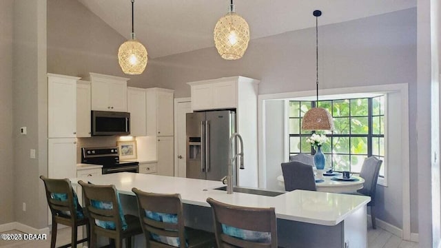 kitchen featuring stainless steel appliances, light countertops, white cabinetry, a sink, and a kitchen breakfast bar