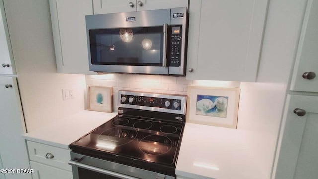 kitchen featuring stainless steel appliances, backsplash, light countertops, and white cabinets