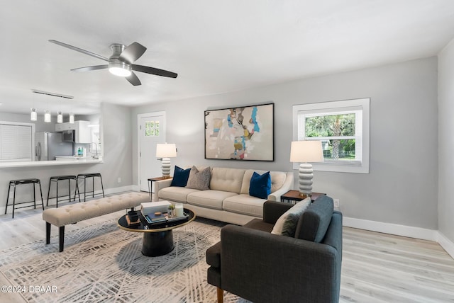 living room featuring ceiling fan, sink, and light hardwood / wood-style floors