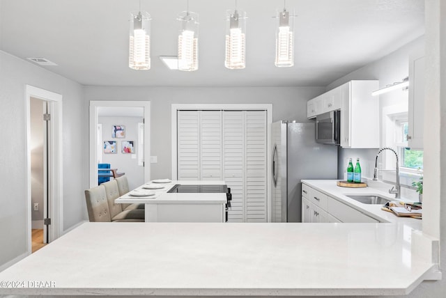 kitchen featuring white cabinets, stainless steel appliances, sink, and decorative light fixtures