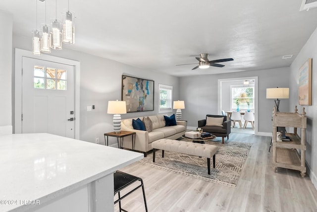 living room with light wood-type flooring, plenty of natural light, and ceiling fan