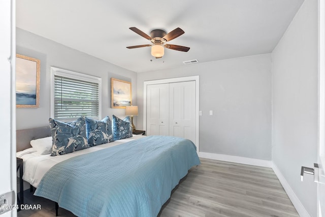 bedroom with a closet, light hardwood / wood-style floors, and ceiling fan