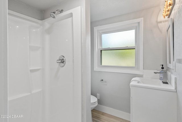 bathroom featuring vanity, hardwood / wood-style flooring, toilet, and a shower