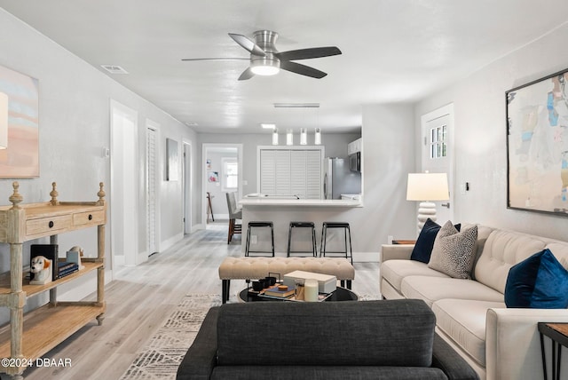 living room with ceiling fan and light hardwood / wood-style flooring