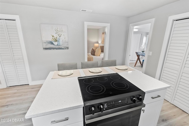 kitchen with white cabinetry, light hardwood / wood-style flooring, stainless steel electric range oven, and a kitchen island