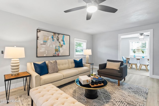 living room featuring wood-type flooring, ceiling fan, and plenty of natural light