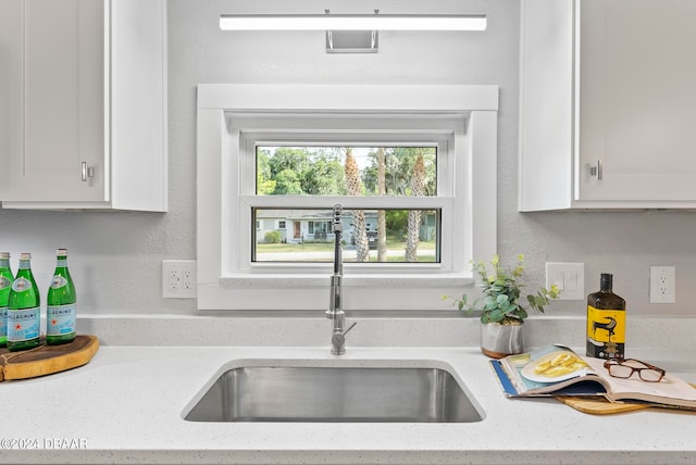 kitchen featuring white cabinets, sink, and light stone countertops