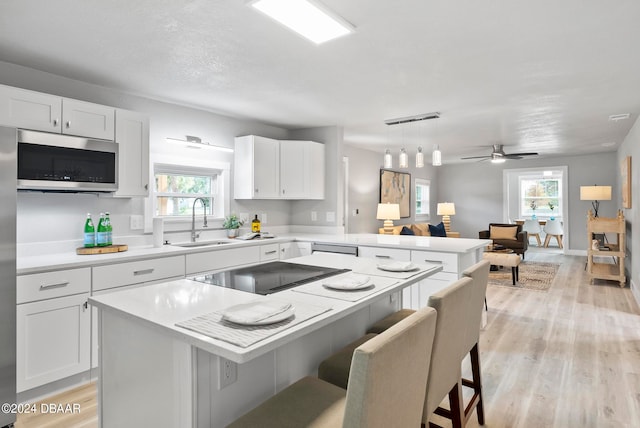 kitchen featuring white cabinets, a kitchen breakfast bar, appliances with stainless steel finishes, and plenty of natural light