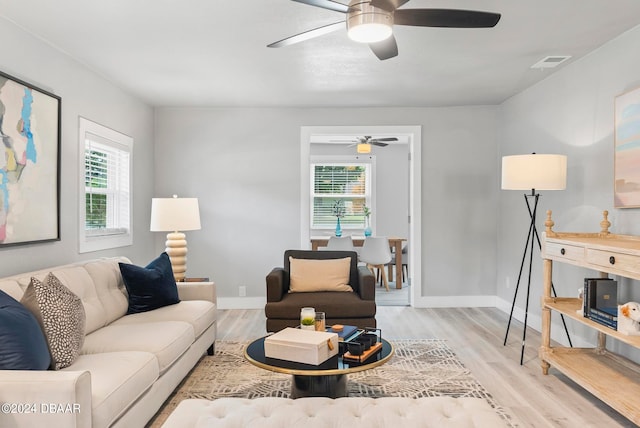 living room featuring light hardwood / wood-style floors, ceiling fan, and plenty of natural light