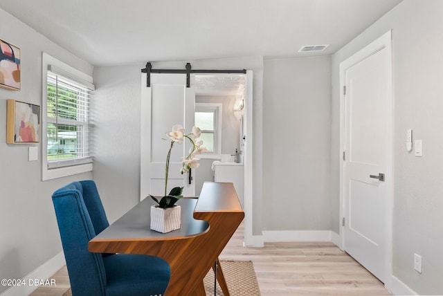 dining space with a barn door, a wealth of natural light, and light hardwood / wood-style flooring