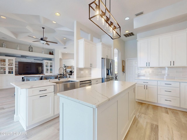 kitchen with arched walkways, appliances with stainless steel finishes, visible vents, and a sink