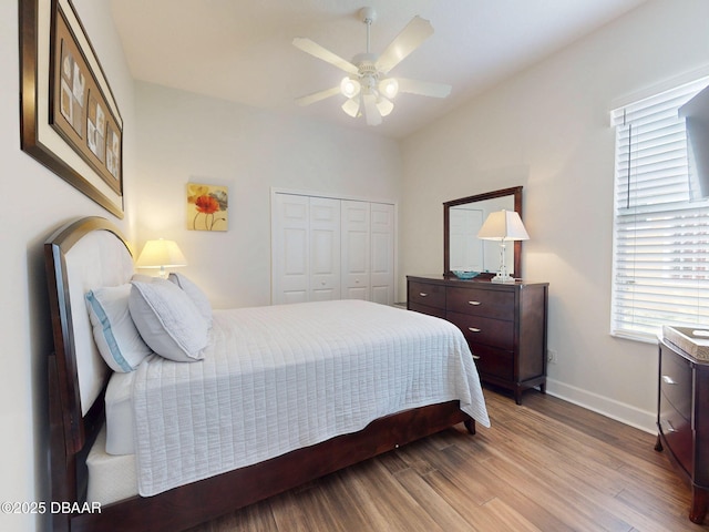 bedroom with baseboards, a ceiling fan, a closet, and wood finished floors