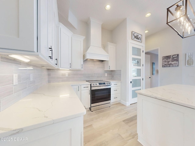 kitchen with decorative backsplash, light wood-style floors, premium range hood, stainless steel electric range, and white cabinets