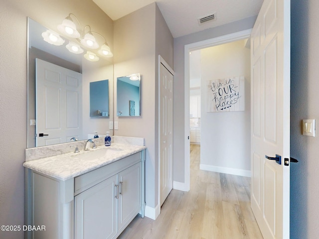 bathroom with visible vents, baseboards, wood finished floors, and vanity