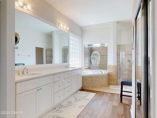 full bathroom featuring a shower stall, a sink, a bath, and wood finished floors