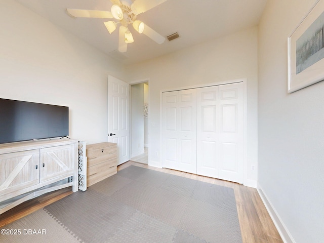 unfurnished bedroom with a ceiling fan, baseboards, wood finished floors, visible vents, and a closet