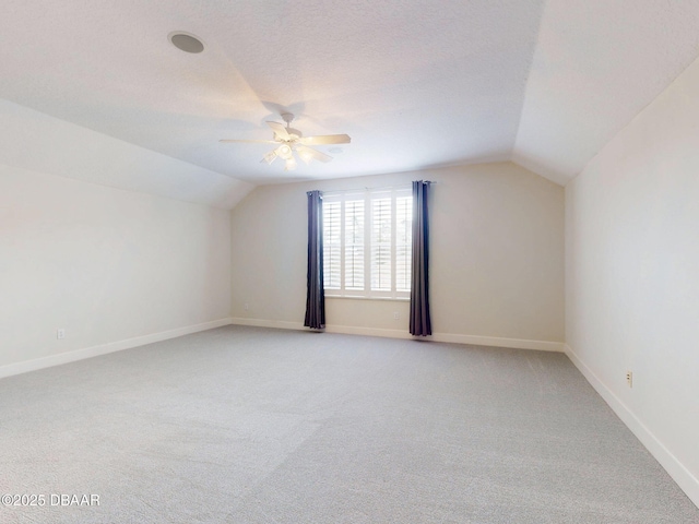 bonus room featuring baseboards, ceiling fan, vaulted ceiling, and light colored carpet