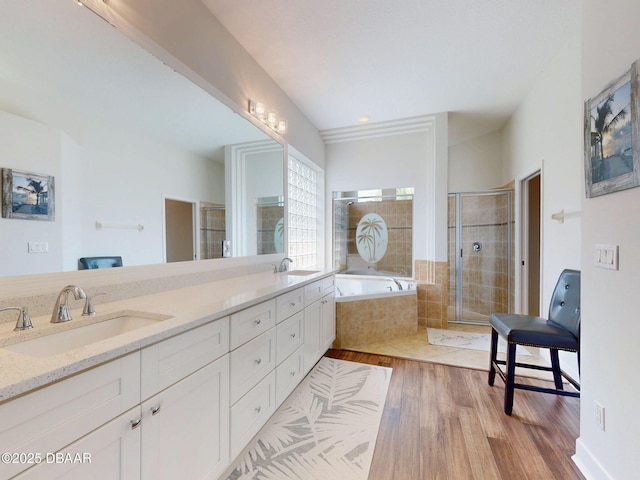 bathroom with a sink, a bath, a stall shower, and wood finished floors