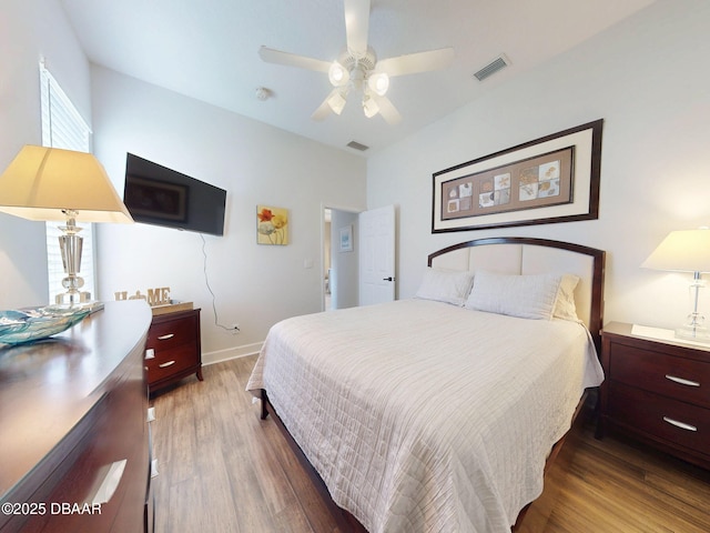 bedroom featuring visible vents, a ceiling fan, baseboards, and wood finished floors